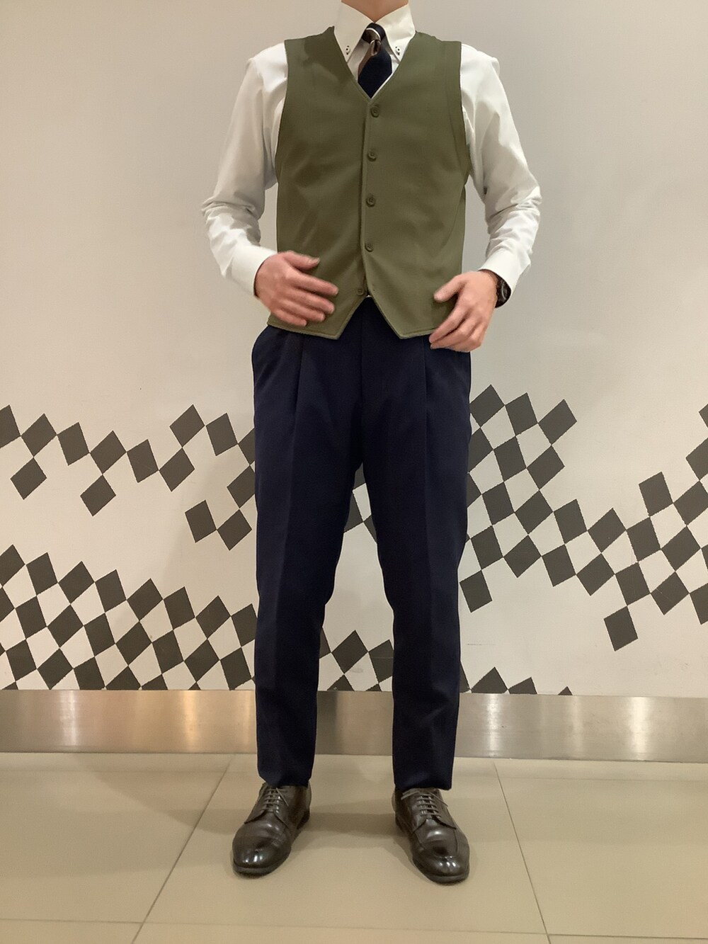 グリーン系のビジネスシャツ、グリーン系のベストを着用したメンズの冬コーディネートの4枚目の写真
