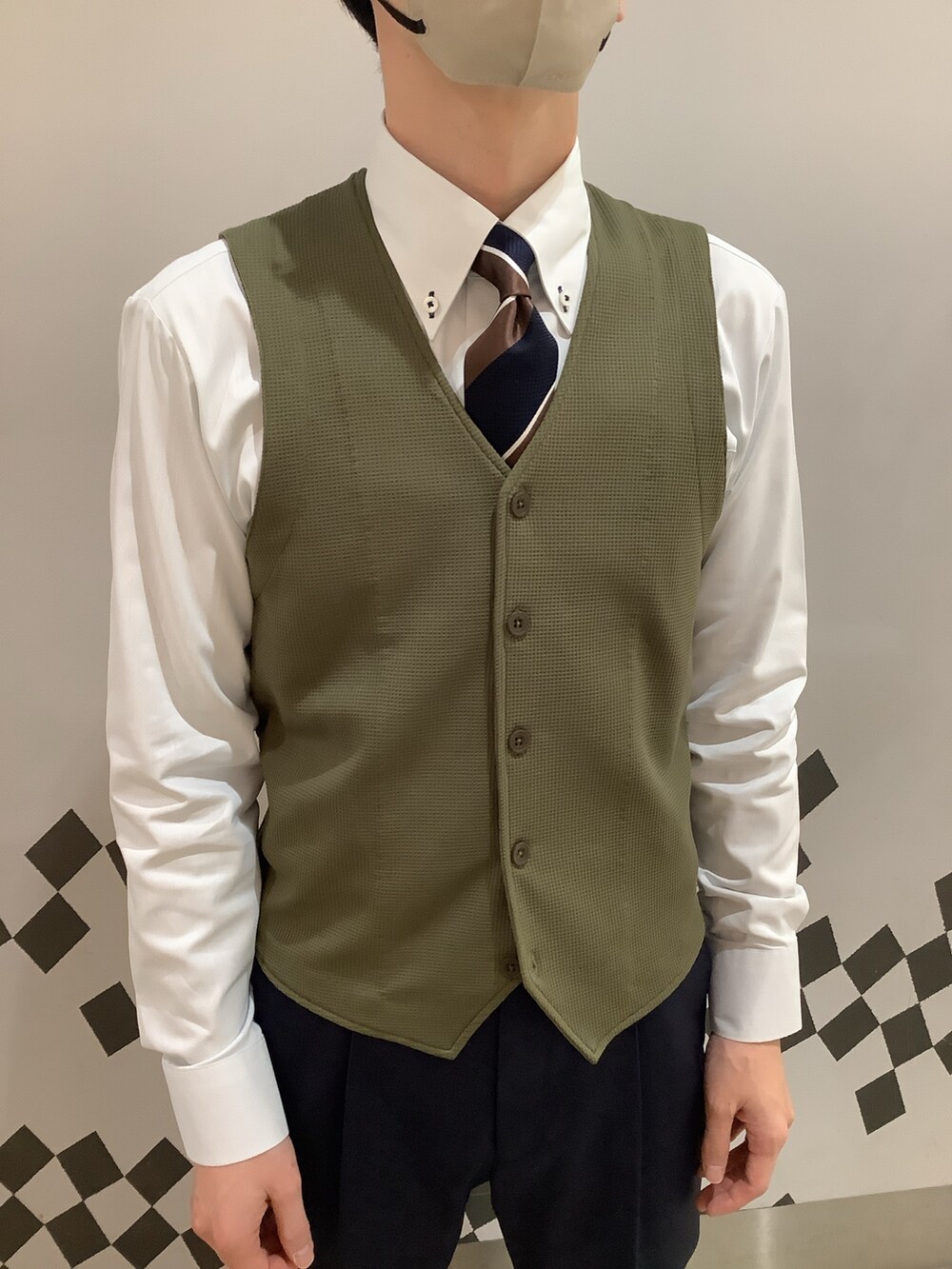 グリーン系のビジネスシャツ、グリーン系のベストを着用したメンズの冬コーディネートの2枚目の写真