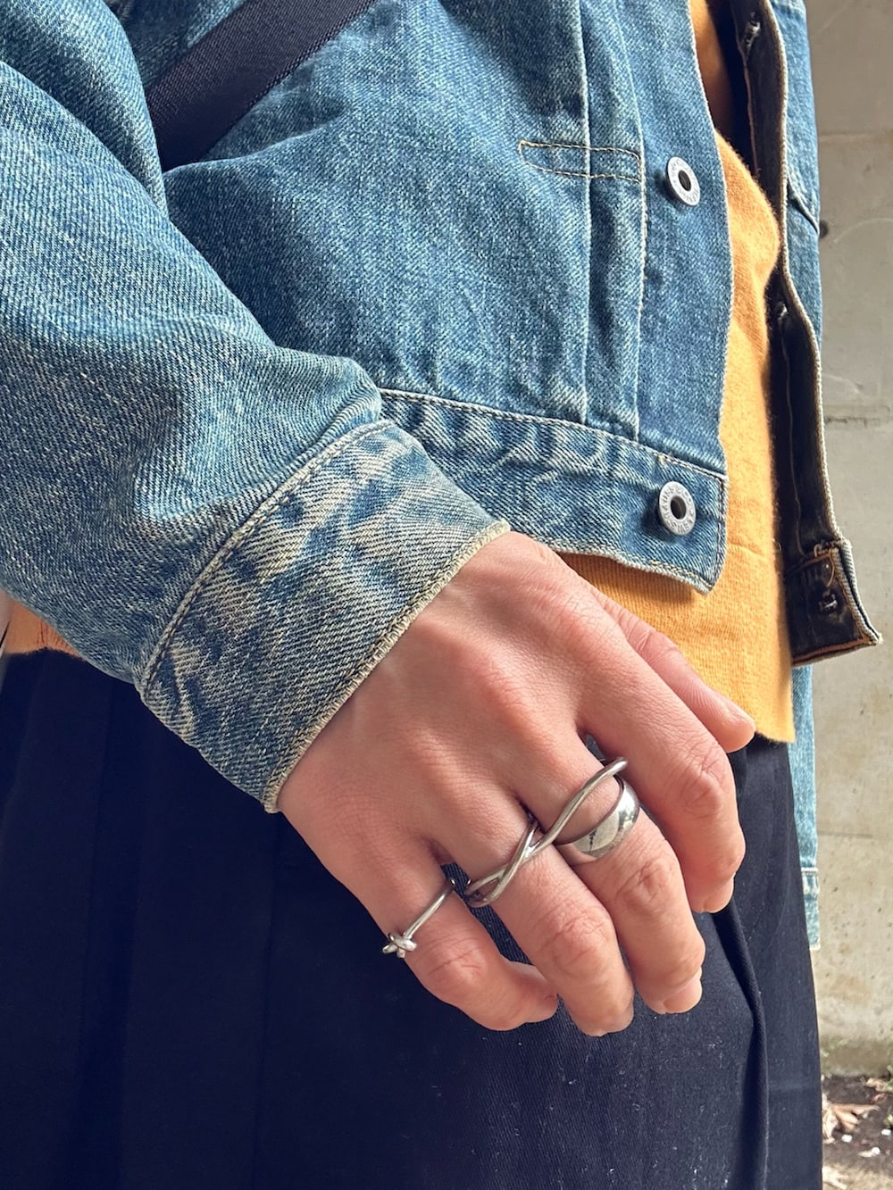 ブルー系のデニムジャケット、ホワイト系のショルダーバッグ、イエロー系のニット/セーターを着用したメンズの春コーディネートの4枚目の写真