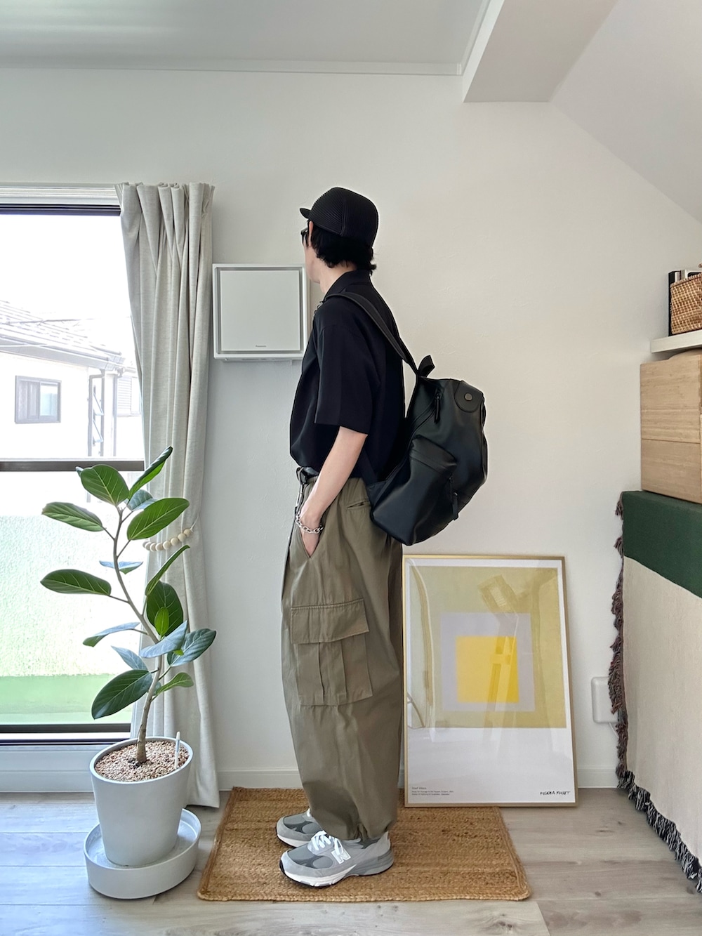 ブラック系のポロシャツ、ブラック系のバックパック/リュック、グリーン系のカーゴパンツを着用したメンズの夏コーディネートの2枚目の写真