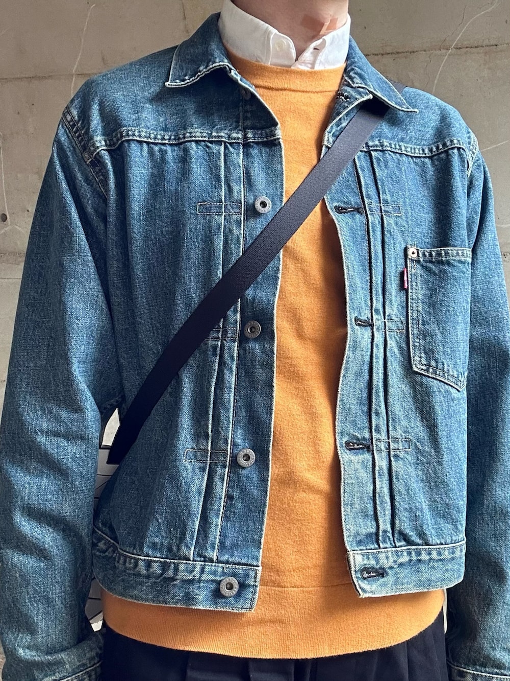 ブルー系のデニムジャケット、ホワイト系のショルダーバッグ、イエロー系のニット/セーターを着用したメンズの春コーディネートの2枚目の写真