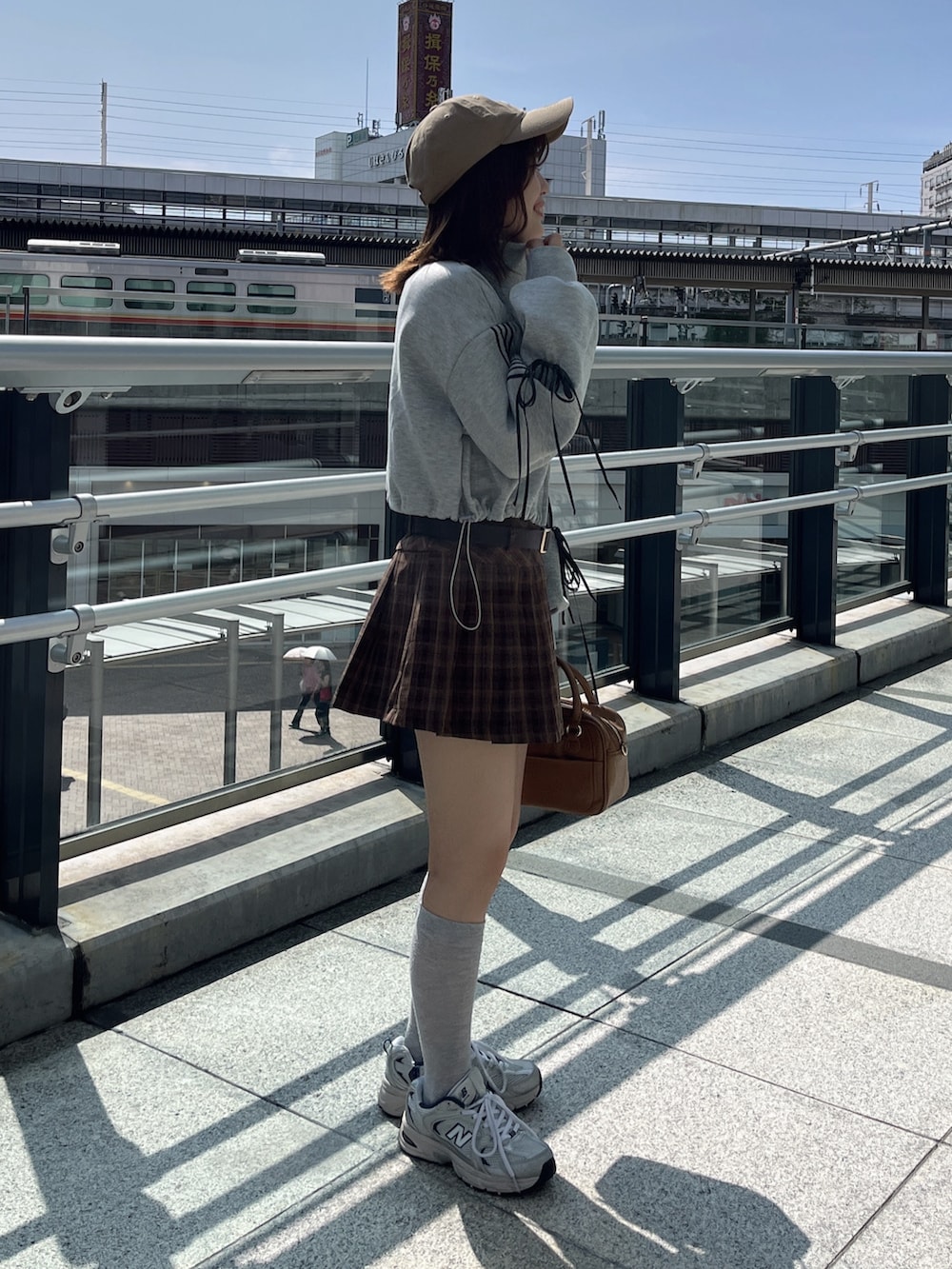 グレー系のスウェット、ブラウン系のスカート、イエロー系のボストンバッグを着用したレディースの秋コーディネートの2枚目の写真