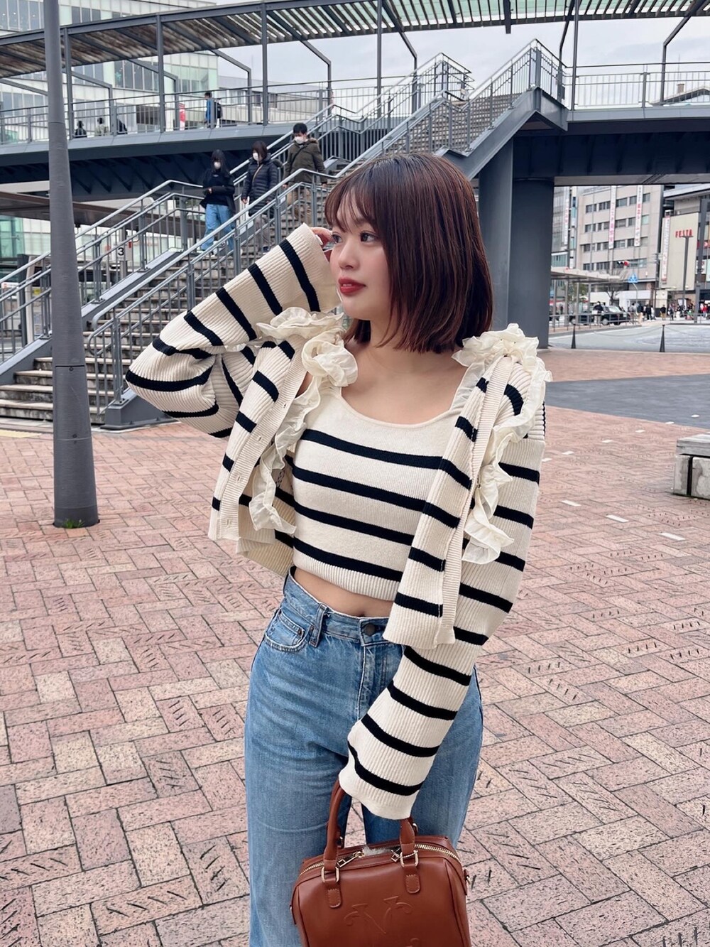 ホワイト系のカーディガン/ボレロ、ホワイト系のその他トップス、ブラウン系のボストンバッグを着用したレディースの冬コーディネートの2枚目の写真