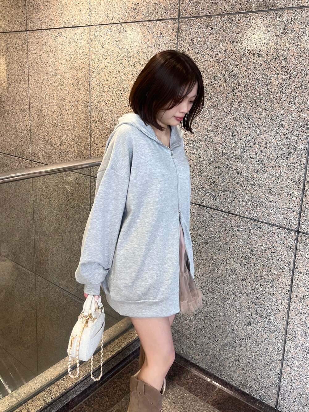 グレー系のパーカー、ホワイト系のショルダーバッグを着用したレディースの冬コーディネートの2枚目の写真