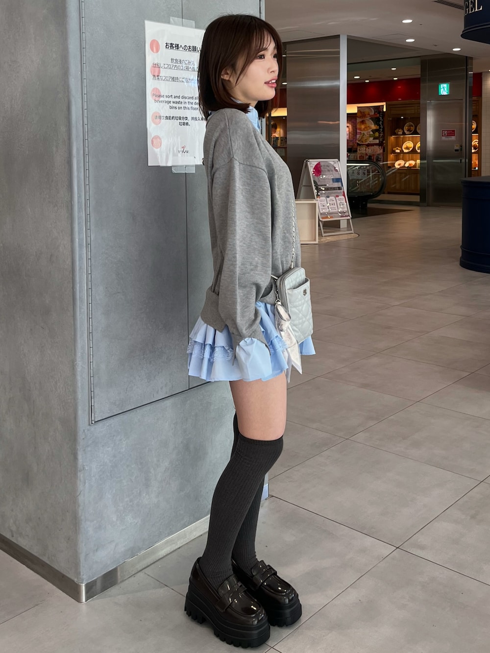 グレー系のワンピース、ブルー系のショルダーバッグ、ブラック系のローファーを着用したレディースの冬コーディネートの2枚目の写真