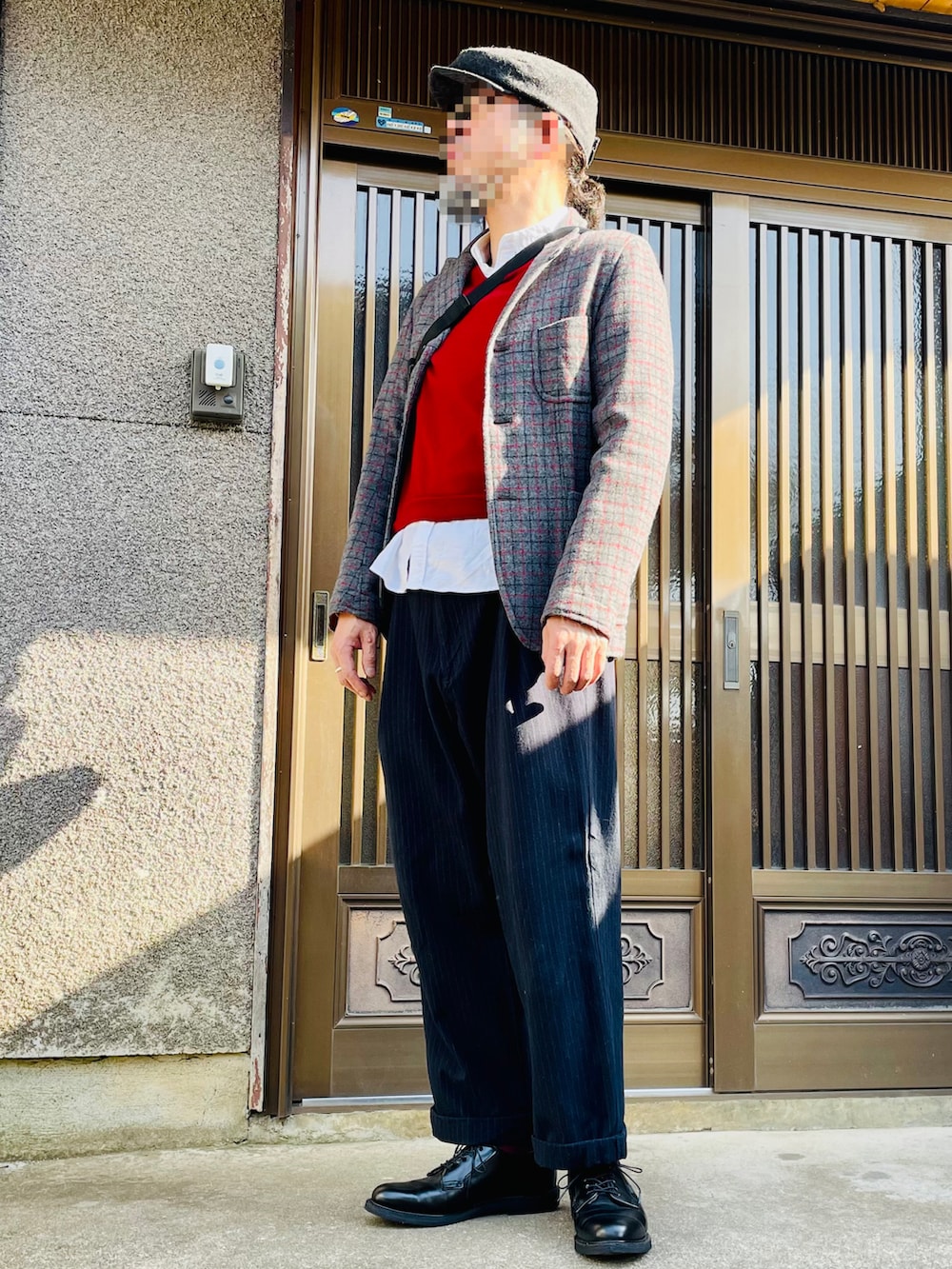 ブラック系のスラックス、ブラック系のドレスシューズ、レッド系のニット/セーターを着用したメンズの春コーディネートの2枚目の写真