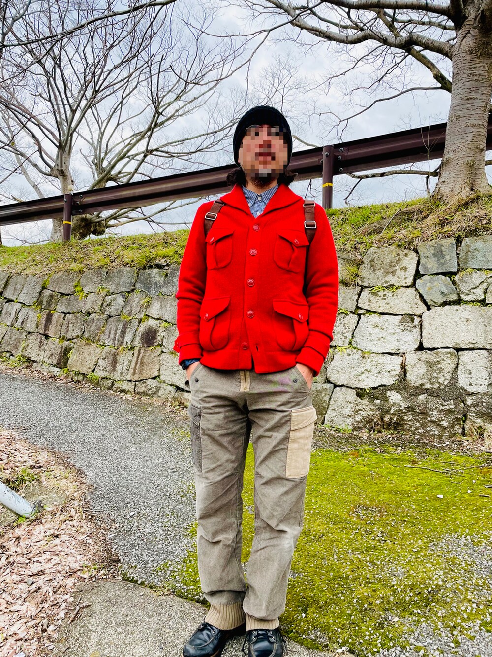 レッド系のニット/セーター、グリーン系のカーゴパンツ、ブラック系のブーツを着用したメンズの春コーディネートの2枚目の写真