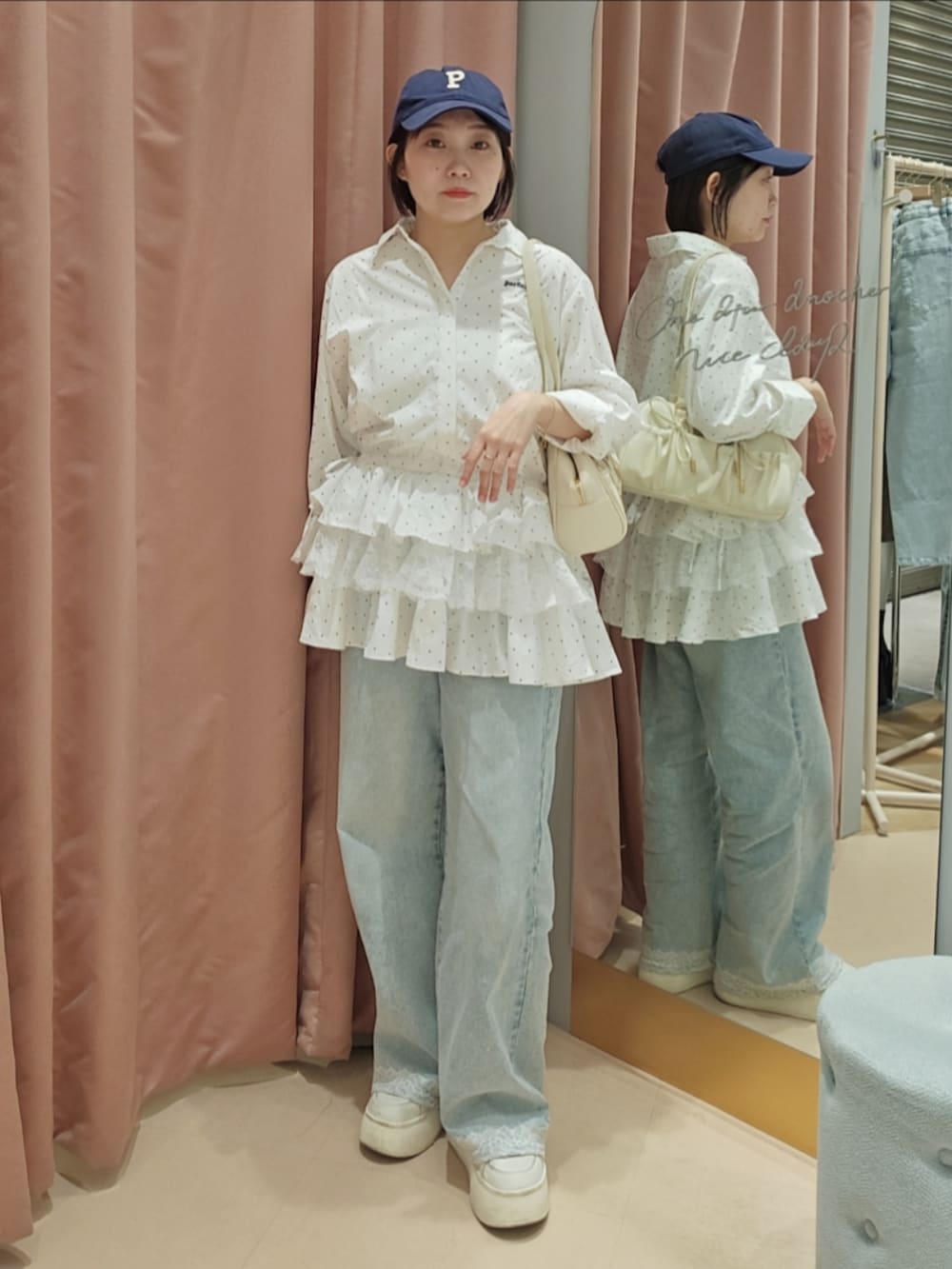 ホワイト系のボストンバッグ、ホワイト系のスニーカー、ブルー系のデニムパンツを着用したレディースの春コーディネートの2枚目の写真