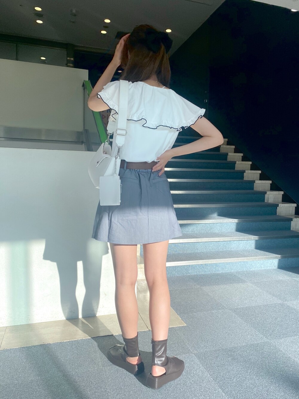 グレー系のスカート、ブラウン系のブーツ、ホワイト系のシャツ/ブラウスを着用したレディースの夏コーディネートの2枚目の写真