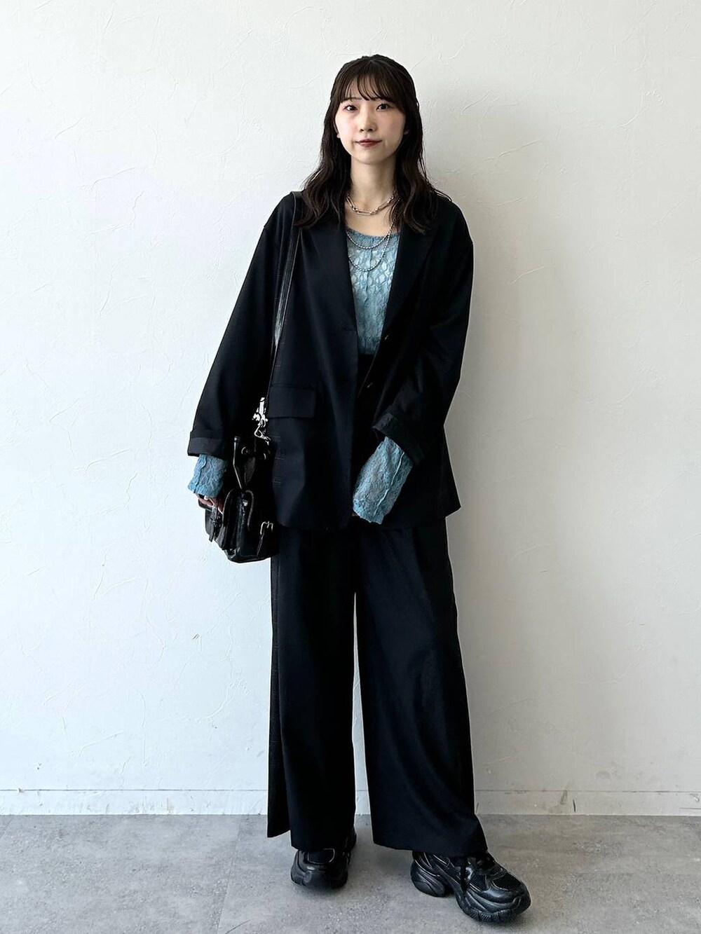 ブラック系のスニーカー、ブラック系のテーラードジャケット、ブラック系のスラックスを着用したレディースの夏コーディネートの7枚目の写真