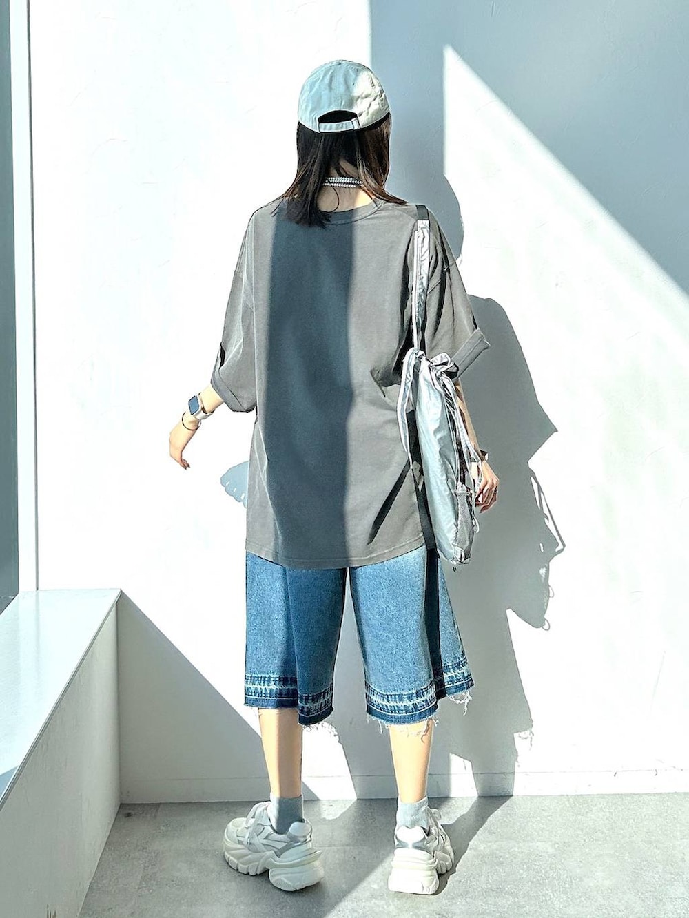 シルバー系のバックパック/リュック、グレー系のTシャツ/カットソー、ブルー系のデニムパンツを着用したレディースの夏コーディネートの4枚目の写真