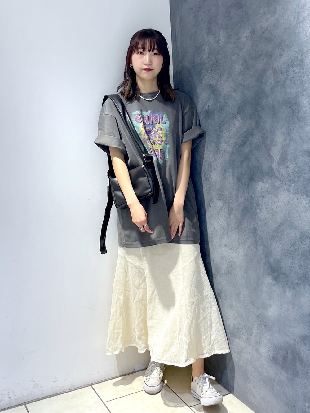 グレー系のTシャツ/カットソー、ホワイト系のスカート、ブラック系のバッグを着用したレディースの春コーディネートの2枚目の写真