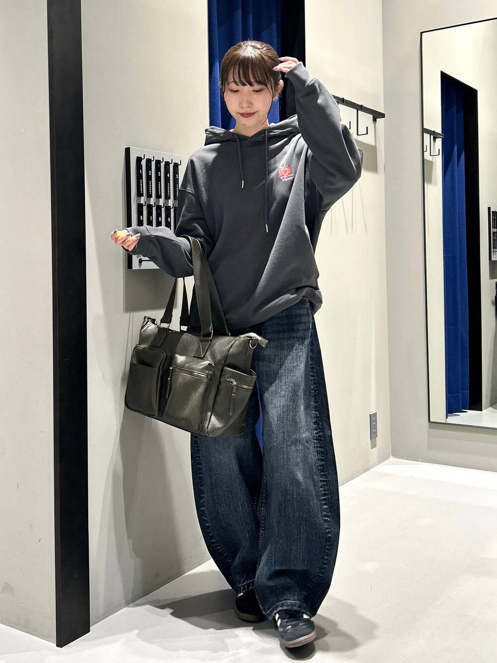 グリーン系のボストンバッグ、グレー系のパーカー、ブルー系のデニムパンツを着用したレディースの秋コーディネートの3枚目の写真