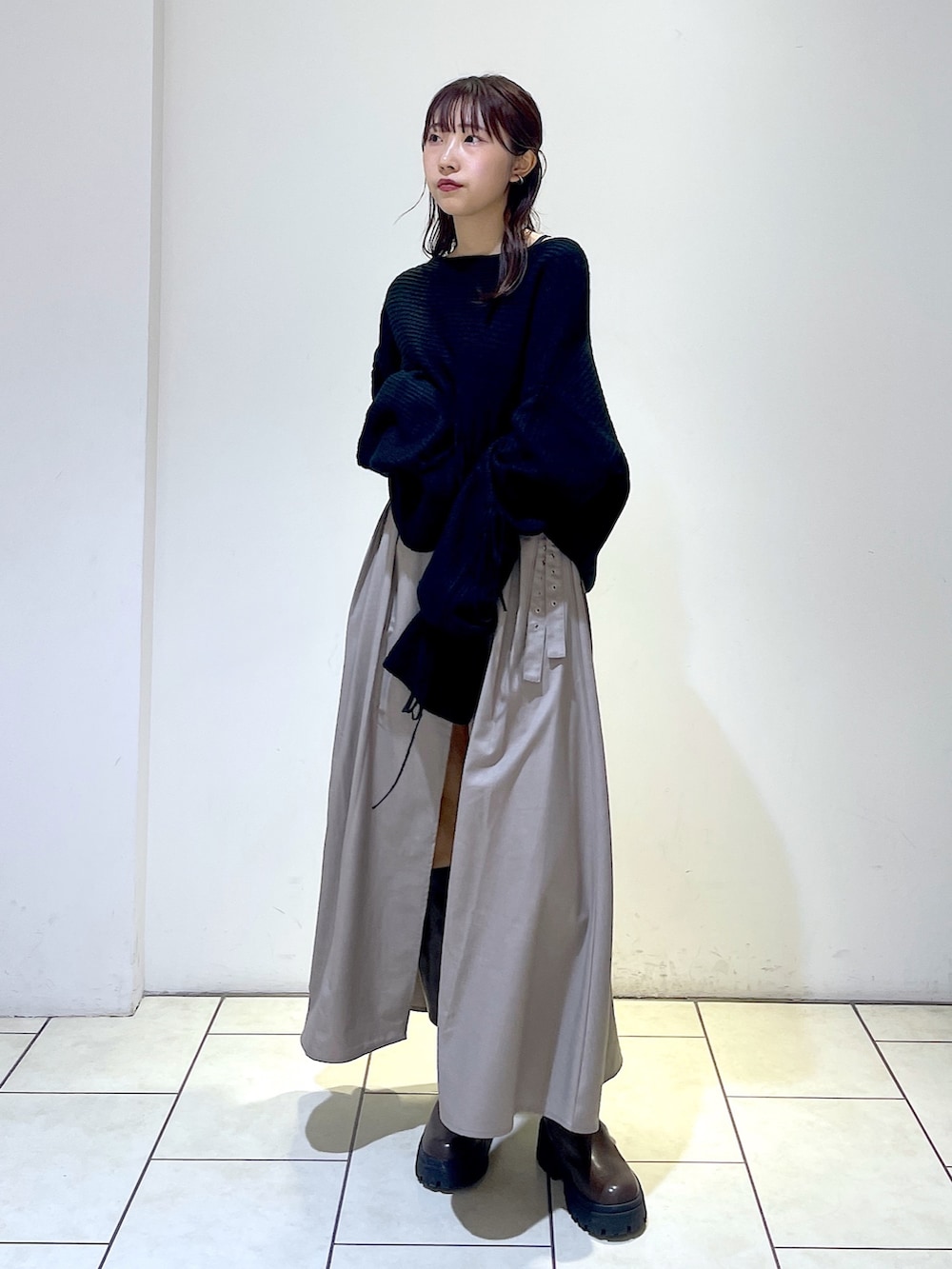 ブラック系のニット/セーター、グレー系のスカート、ブラウン系のブーツを着用したレディースの秋コーディネートの4枚目の写真