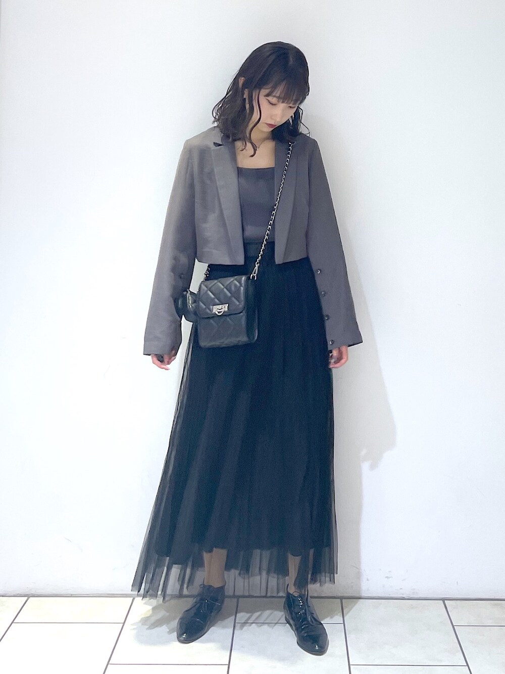 グレー系のテーラードジャケット、グレー系のタンクトップ、ブラック系のスカートを着用したレディースの春コーディネートの3枚目の写真