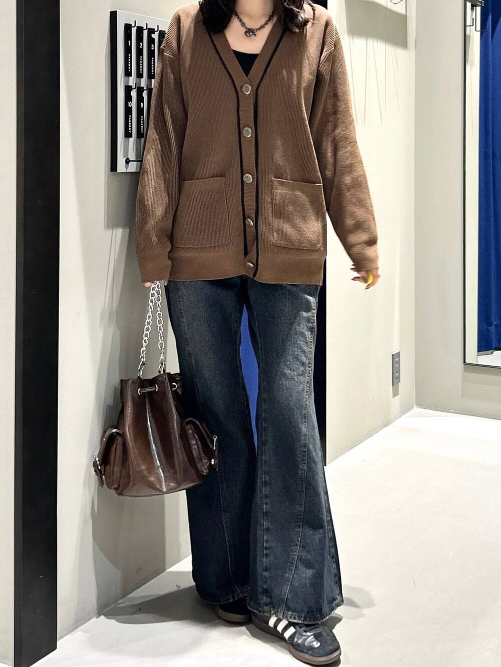 ブラック系のキャミソール、ブルー系のデニムパンツ、ブラウン系のショルダーバッグを着用したレディースの秋コーディネートの8枚目の写真