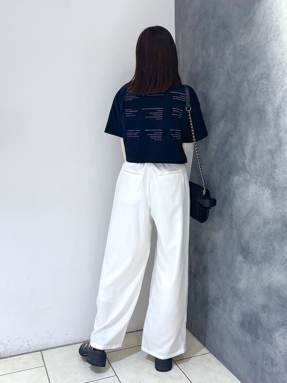 ブラック系のTシャツ/カットソー、ホワイト系のパンツ、ブラック系のサンダルを着用したレディースの春コーディネートの4枚目の写真