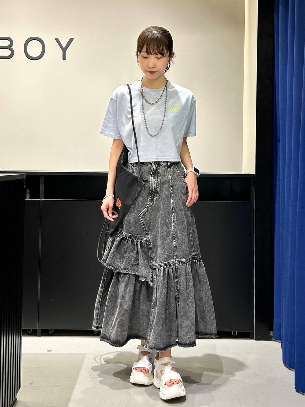 ホワイト系のサンダル、ブラック系のデニムスカート、ブルー系のTシャツ/カットソーを着用したレディースの春コーディネートの2枚目の写真