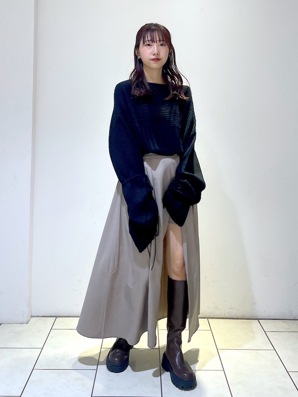 ブラック系のニット/セーター、グレー系のスカート、ブラウン系のブーツを着用したレディースの秋コーディネートの2枚目の写真