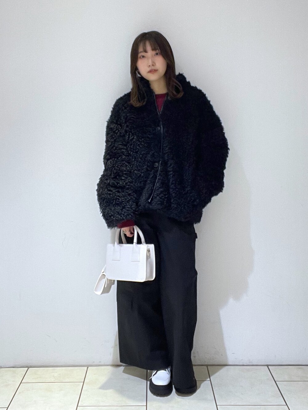 ブラック系のブルゾン、レッド系のスウェット、ホワイト系のバッグを着用したレディースの冬コーディネートの2枚目の写真