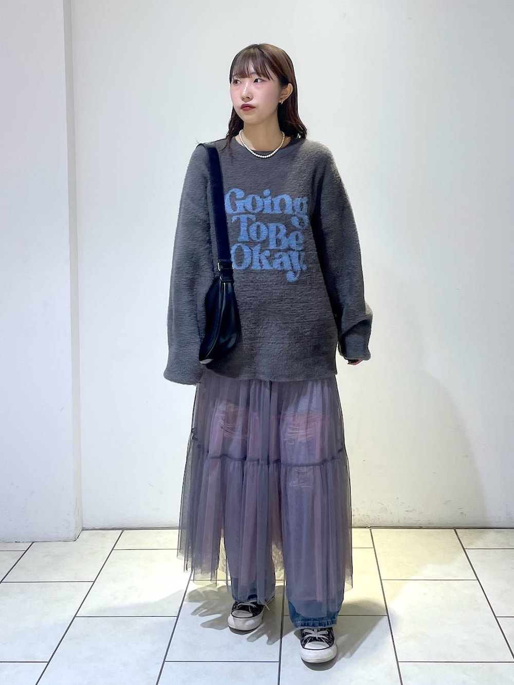 ブルー系のデニムパンツ、ブラック系のショルダーバッグ、グレー系のニット/セーターを着用したレディースの冬コーディネートの2枚目の写真