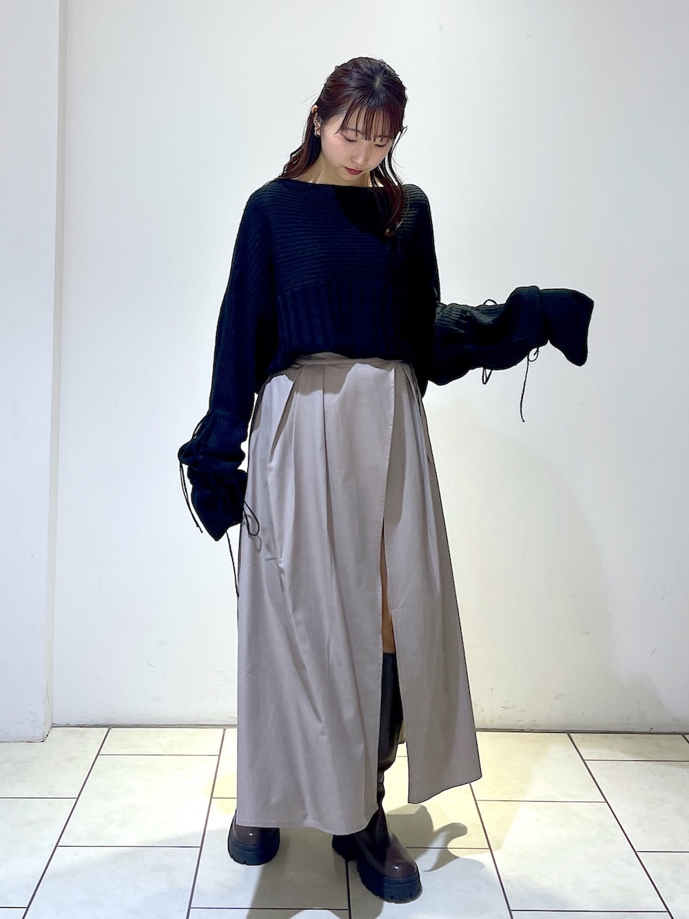 ブラック系のニット/セーター、グレー系のスカート、ブラウン系のブーツを着用したレディースの秋コーディネートの3枚目の写真