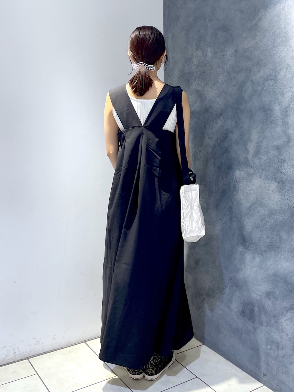 ブラック系のジャンパースカート、ホワイト系のタンクトップ、ホワイト系のショルダーバッグを着用したレディースの夏コーディネートの3枚目の写真