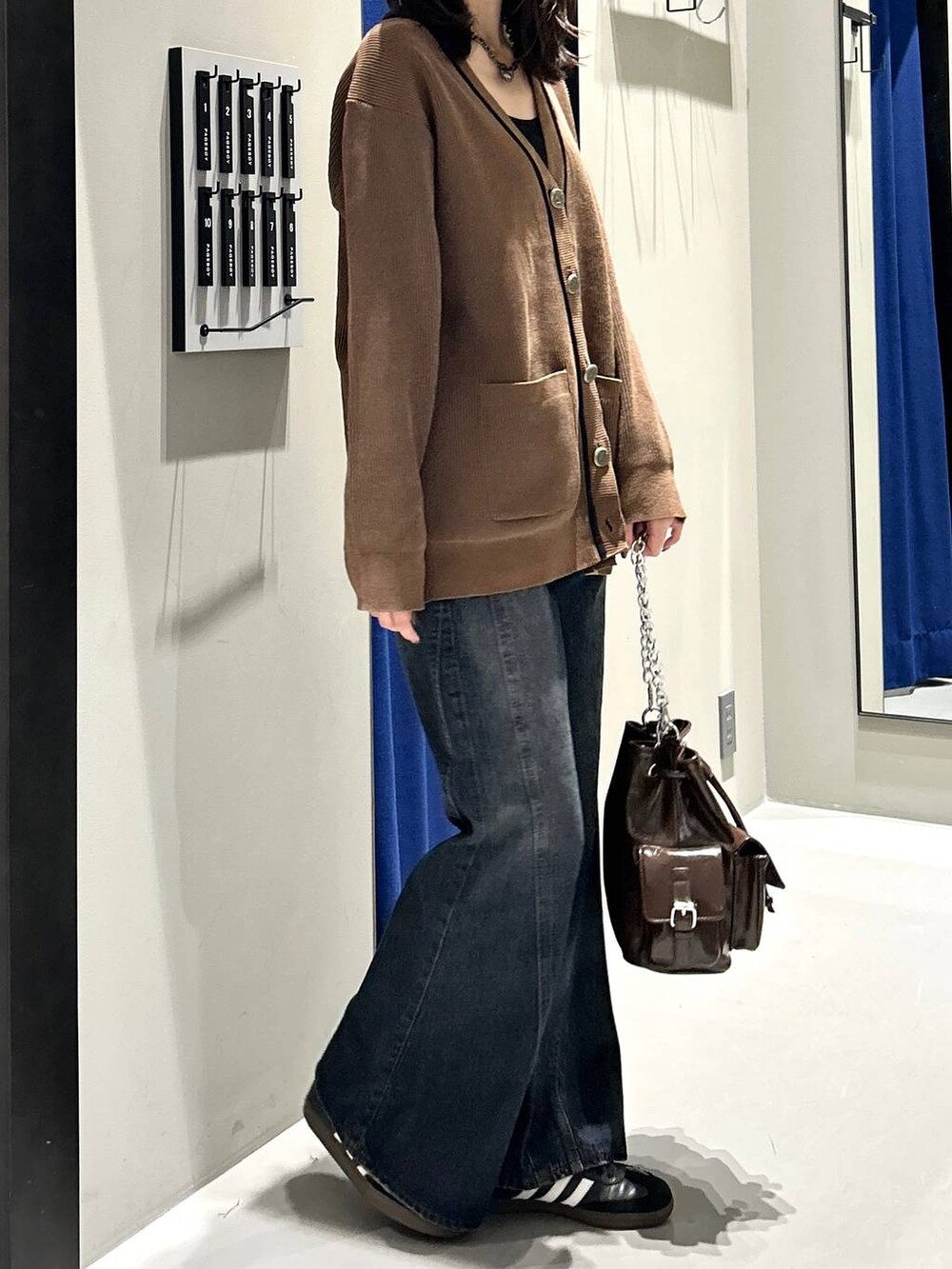 ブラック系のキャミソール、ブルー系のデニムパンツ、ブラウン系のショルダーバッグを着用したレディースの秋コーディネートの7枚目の写真