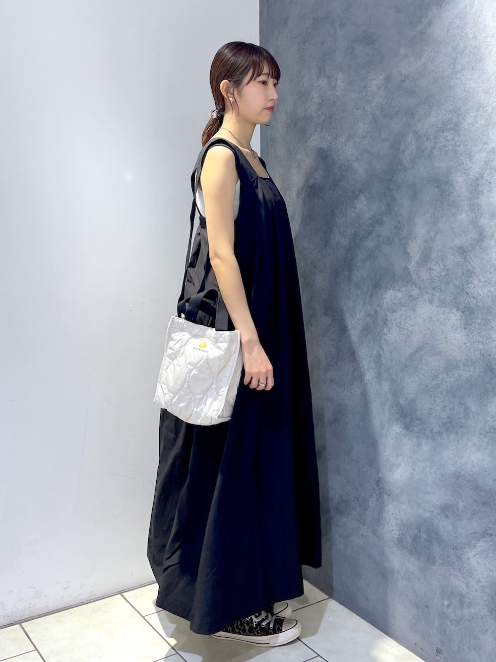 ブラック系のジャンパースカート、ホワイト系のタンクトップ、ホワイト系のショルダーバッグを着用したレディースの夏コーディネートの2枚目の写真