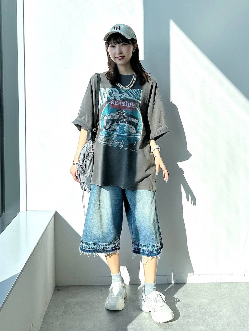 シルバー系のバックパック/リュック、グレー系のTシャツ/カットソー、ブルー系のデニムパンツを着用したレディースの夏コーディネートの2枚目の写真
