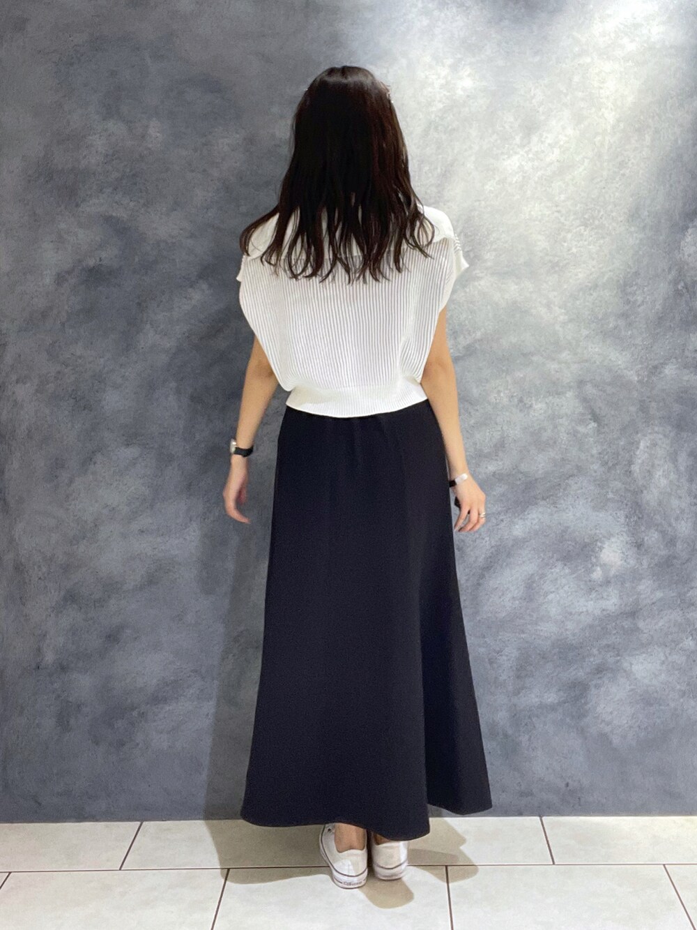 ホワイト系のニット/セーター、ブラック系のスカート、ホワイト系のスニーカーを着用したレディースの夏コーディネートの3枚目の写真