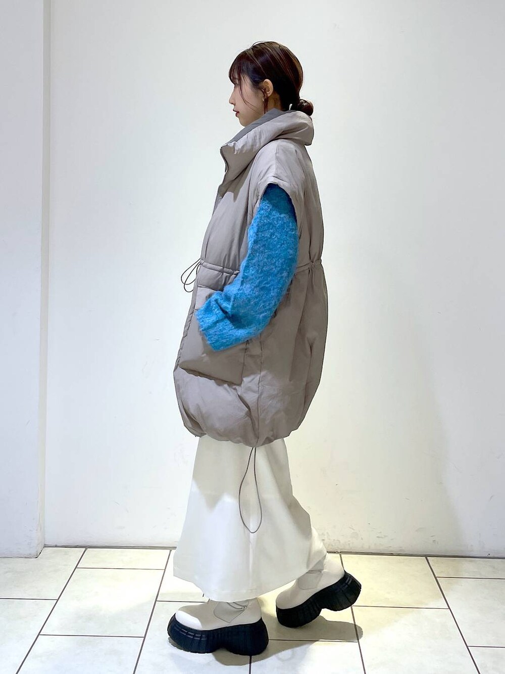 ホワイト系のスカート、ブラウン系のブルゾン、ホワイト系のショルダーバッグを着用したレディースの冬コーディネートの4枚目の写真