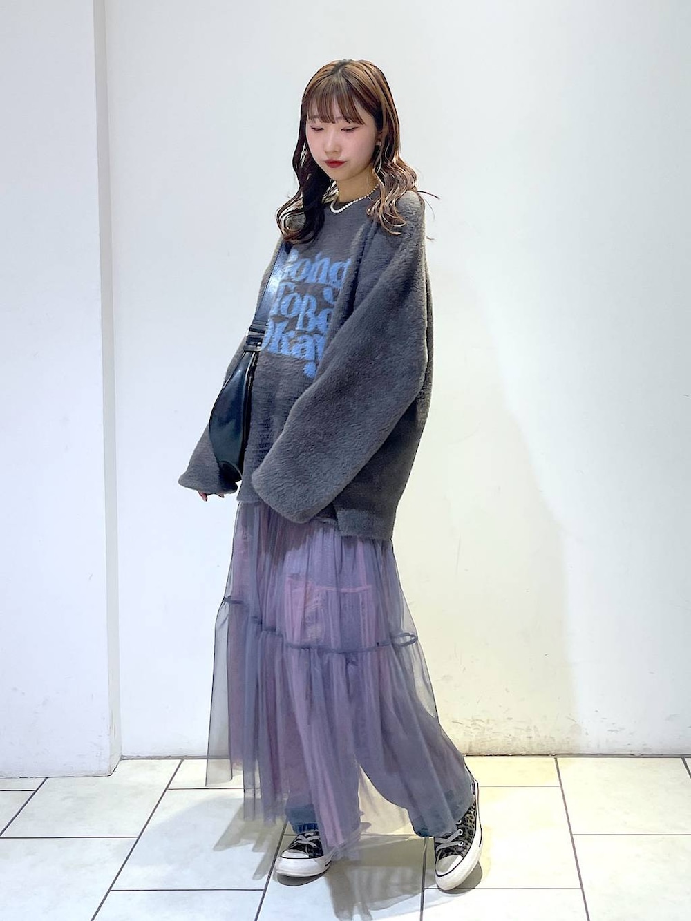 ブルー系のデニムパンツ、ブラック系のショルダーバッグ、グレー系のニット/セーターを着用したレディースの冬コーディネートの3枚目の写真