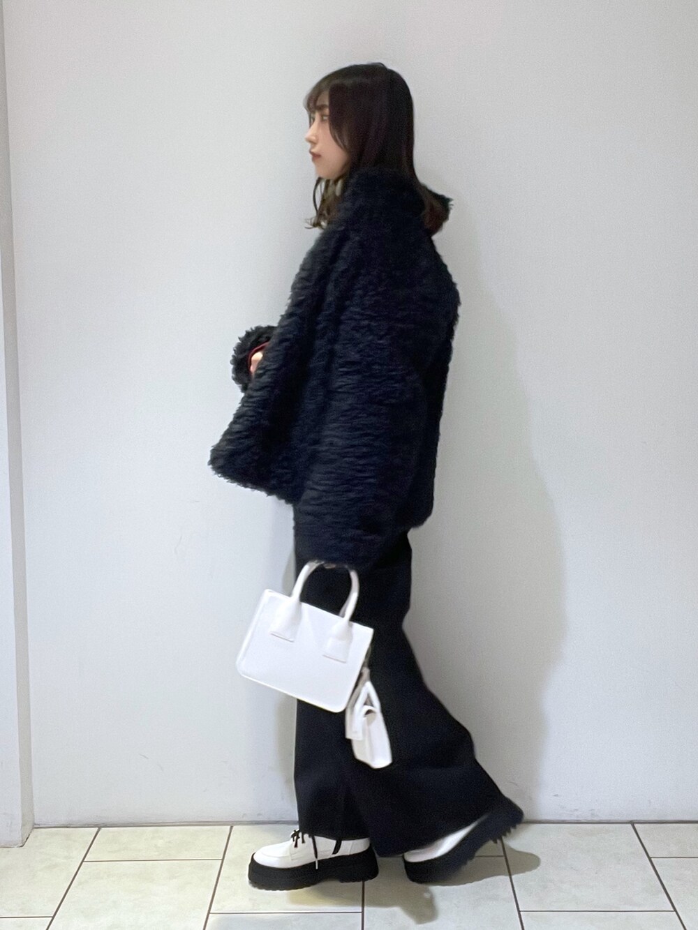 ブラック系のブルゾン、レッド系のスウェット、ホワイト系のバッグを着用したレディースの冬コーディネートの3枚目の写真