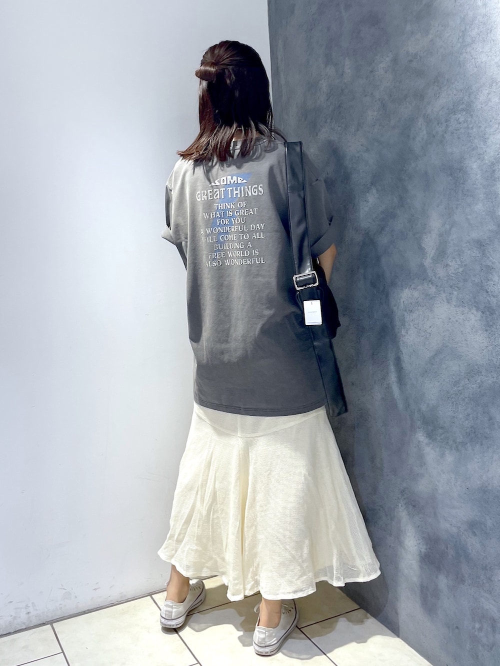 グレー系のTシャツ/カットソー、ホワイト系のスカート、ブラック系のバッグを着用したレディースの春コーディネートの4枚目の写真