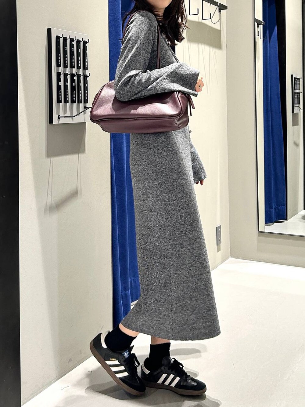 グレー系のワンピース、レッド系のボストンバッグ、ブラック系のキャップを着用したレディースの秋コーディネートの6枚目の写真