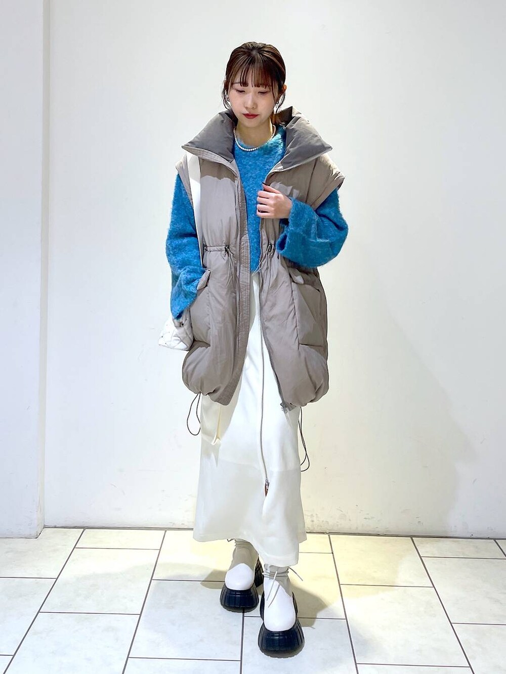 ホワイト系のスカート、ブラウン系のブルゾン、ホワイト系のショルダーバッグを着用したレディースの冬コーディネートの3枚目の写真