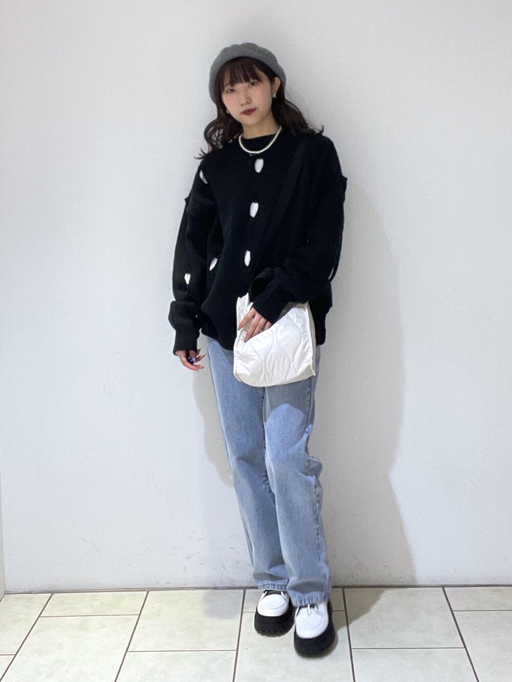 ブラック系のニット/セーター、ホワイト系のTシャツ/カットソー、ブルー系のデニムパンツを着用したレディースの冬コーディネートの2枚目の写真