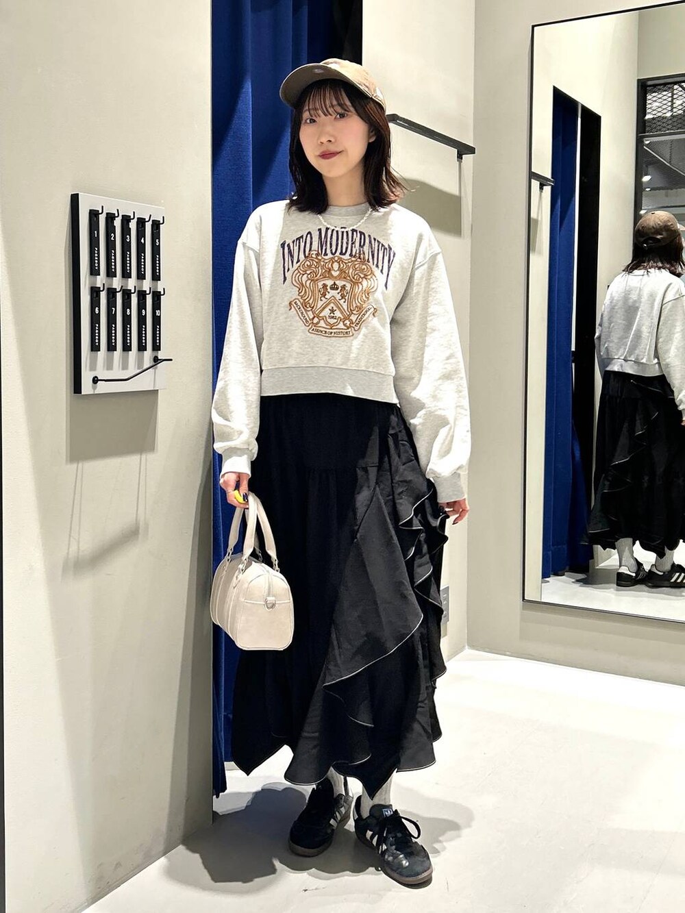 ブラック系のスカート、ホワイト系のボストンバッグ、グレー系のスウェットを着用したレディースの冬コーディネートの2枚目の写真