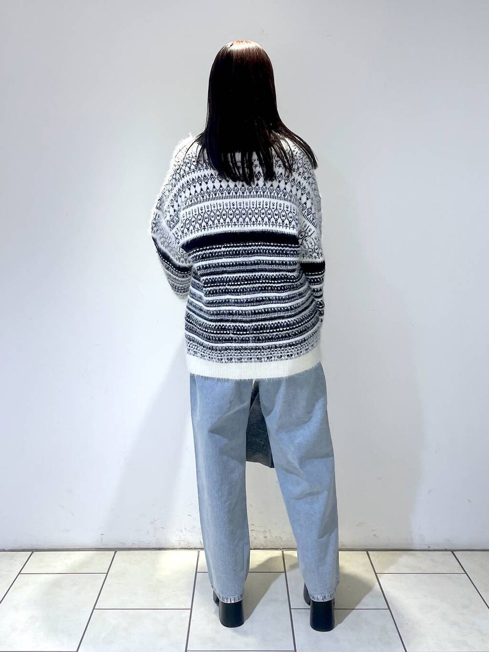 ブラック系のブーツ、ブラック系のニット/セーター、ブラック系のトートバッグを着用したレディースの冬コーディネートの3枚目の写真