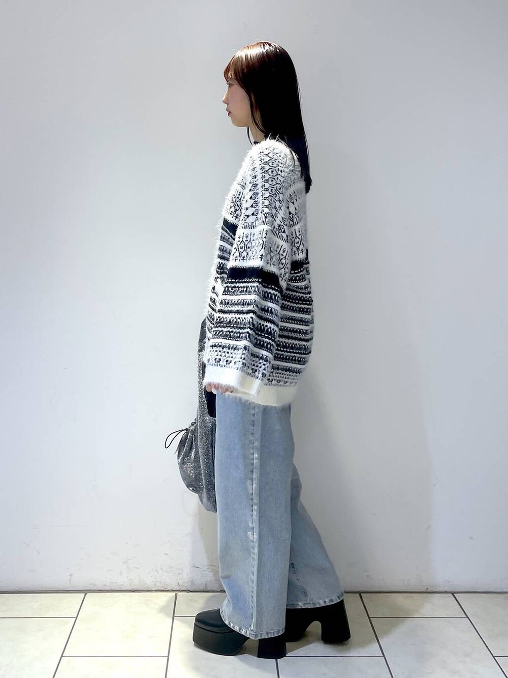 ブラック系のブーツ、ブラック系のニット/セーター、ブラック系のトートバッグを着用したレディースの冬コーディネートの2枚目の写真