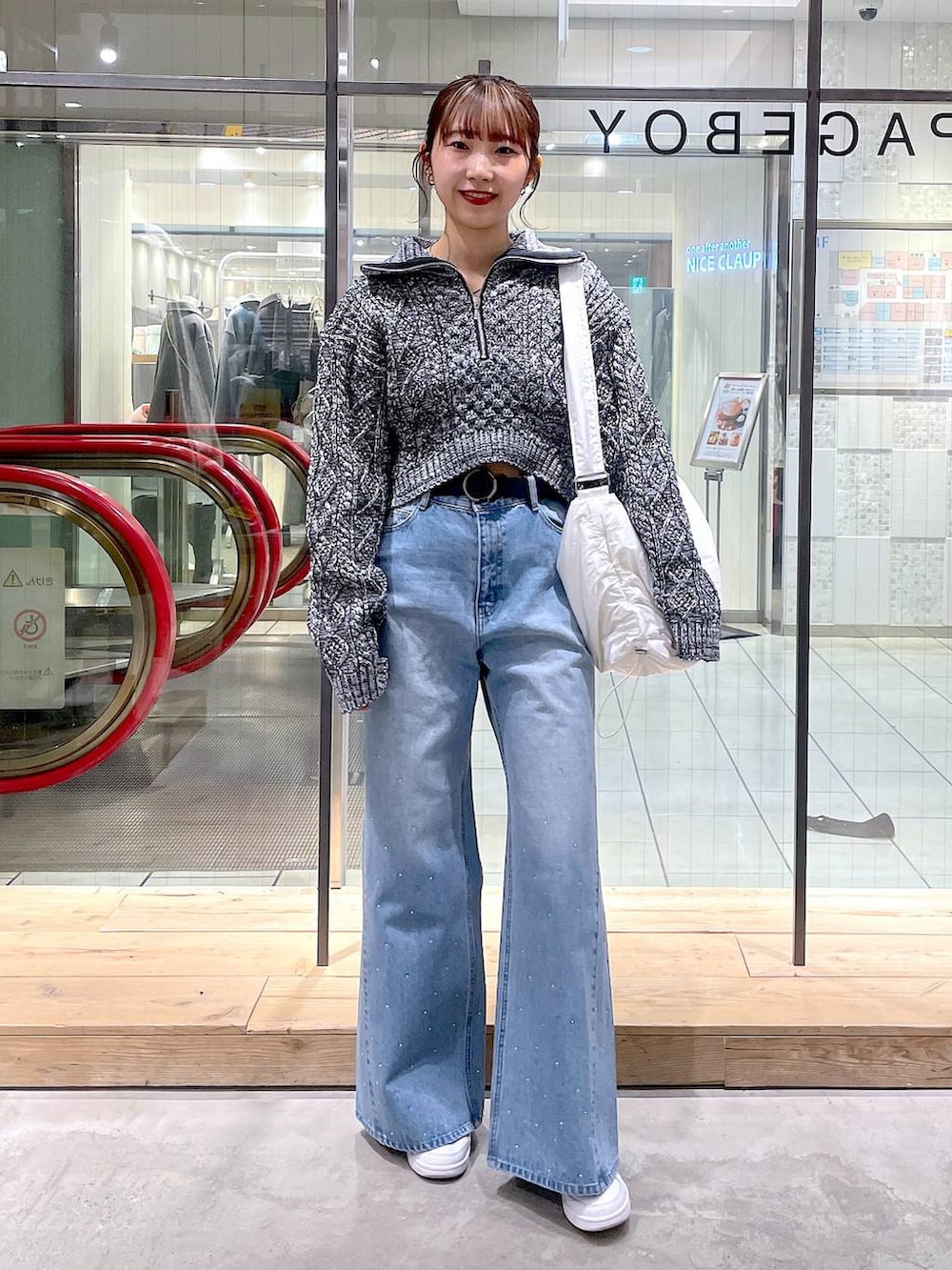 ホワイト系のショルダーバッグ、グレー系のニット/セーター、ブルー系のデニムパンツを着用したレディースの冬コーディネートの2枚目の写真