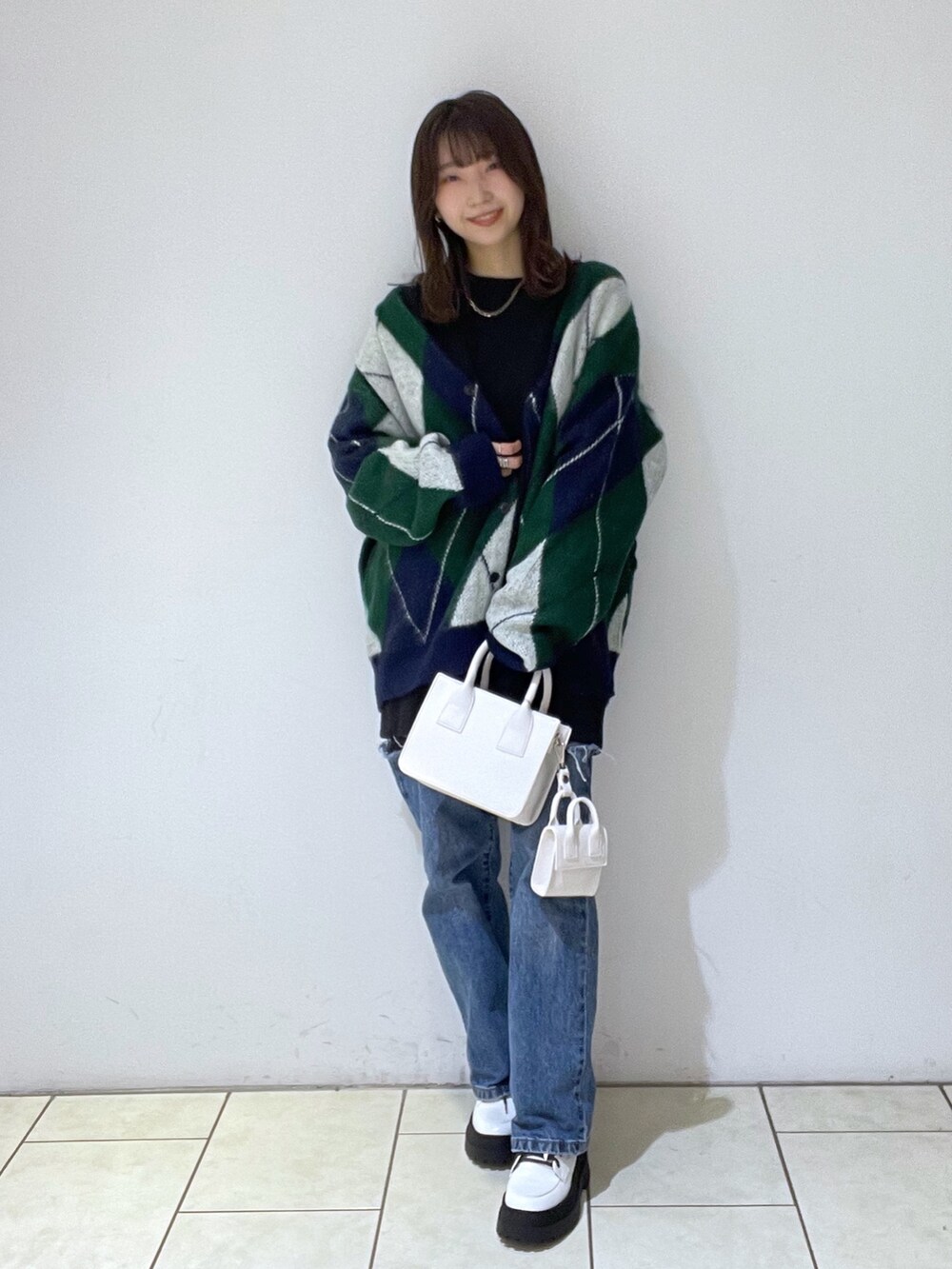 グリーン系のカーディガン/ボレロ、ブラック系のスウェット、ブルー系のデニムパンツを着用したレディースの冬コーディネートの2枚目の写真