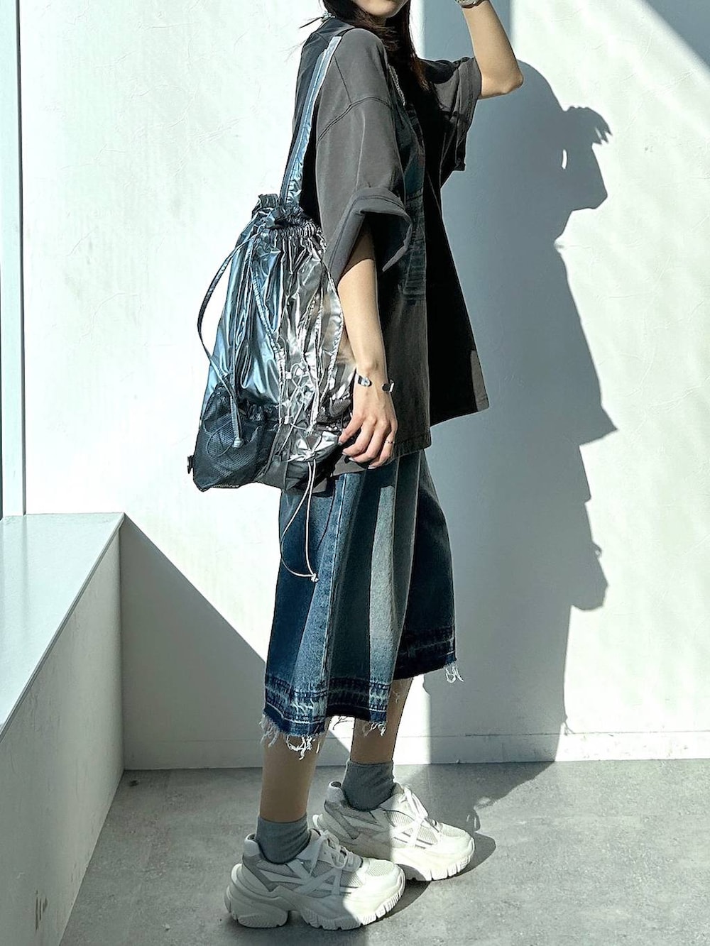 シルバー系のバックパック/リュック、グレー系のTシャツ/カットソー、ブルー系のデニムパンツを着用したレディースの夏コーディネートの3枚目の写真