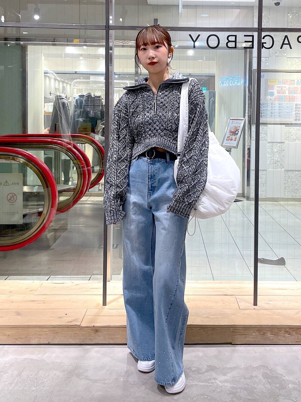 ホワイト系のショルダーバッグ、グレー系のニット/セーター、ブルー系のデニムパンツを着用したレディースの冬コーディネートの3枚目の写真