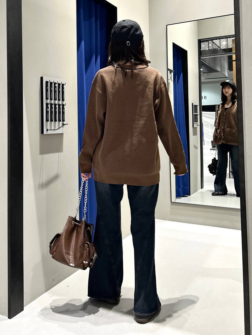 ブラック系のキャミソール、ブルー系のデニムパンツ、ブラウン系のショルダーバッグを着用したレディースの秋コーディネートの10枚目の写真