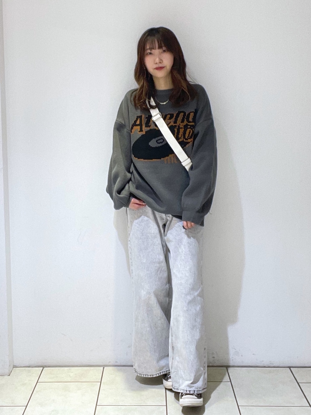 グレー系のニット/セーター、ホワイト系のボディバッグ/ウエストポーチ、ブラウン系のスニーカーを着用したレディースの冬コーディネートの2枚目の写真