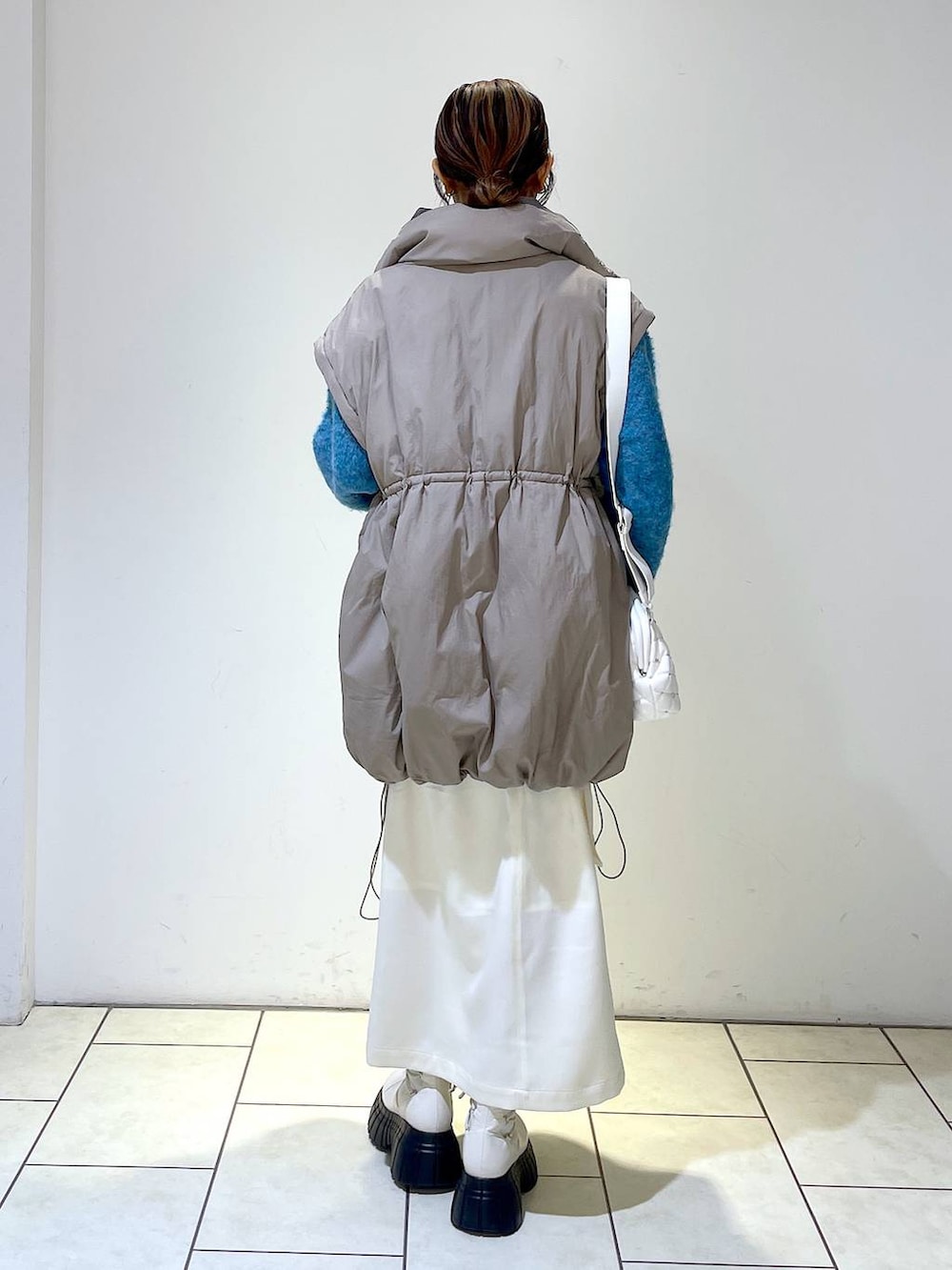 ホワイト系のスカート、ブラウン系のブルゾン、ホワイト系のショルダーバッグを着用したレディースの冬コーディネートの5枚目の写真