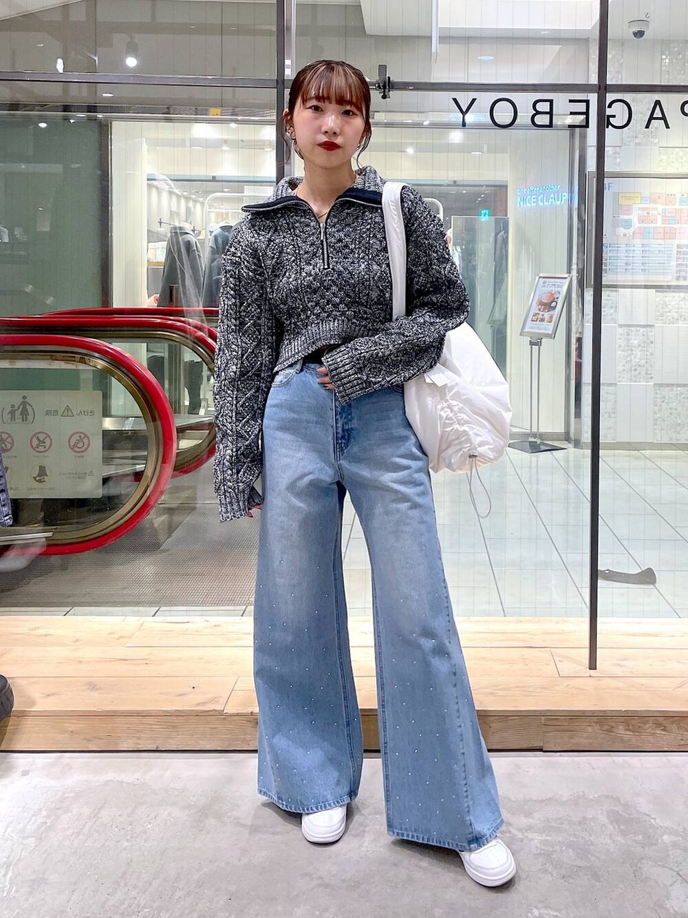 ホワイト系のショルダーバッグ、グレー系のニット/セーター、ブルー系のデニムパンツを着用したレディースの冬コーディネートの4枚目の写真