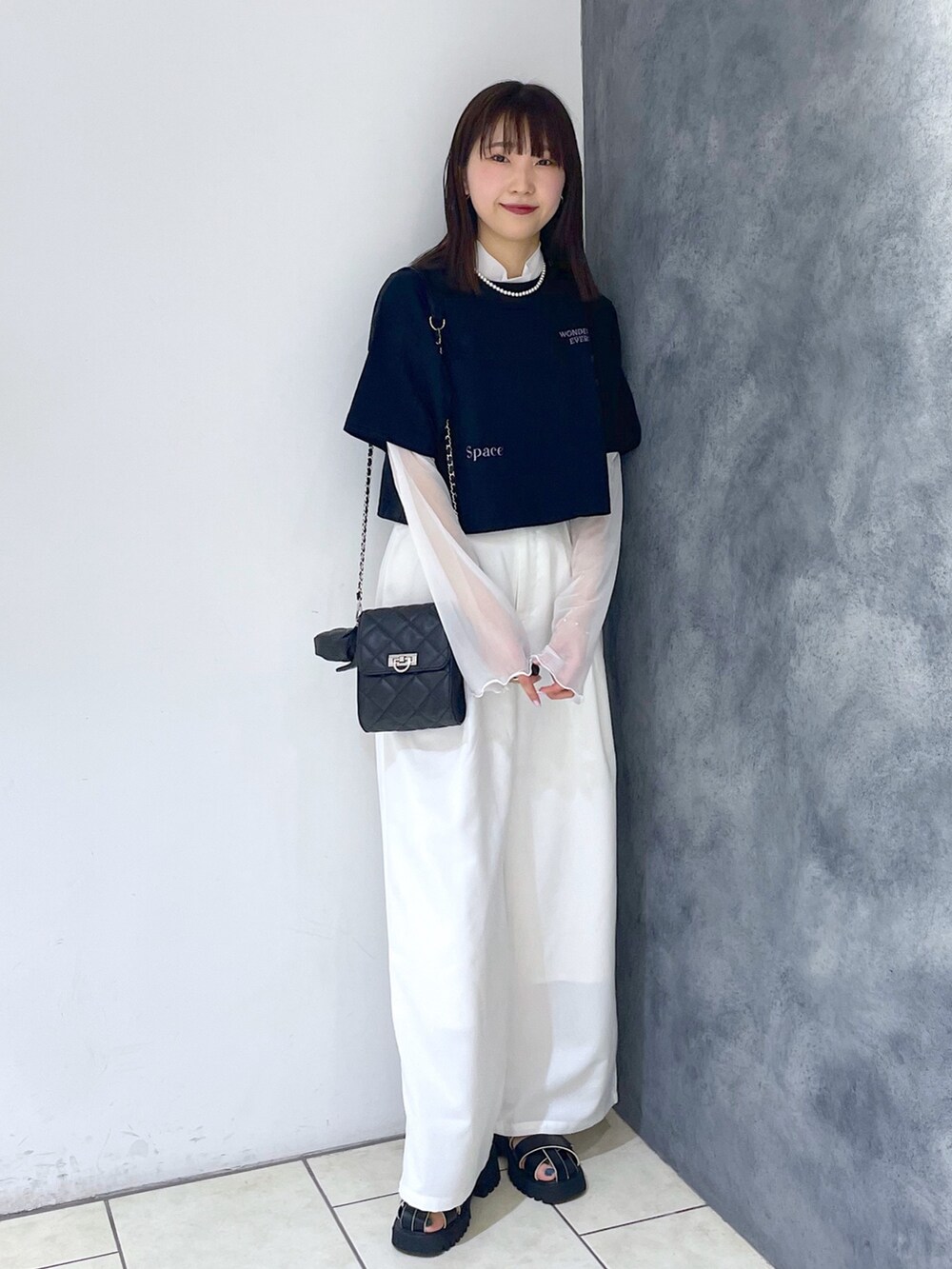 ブラック系のTシャツ/カットソー、ホワイト系のパンツ、ブラック系のサンダルを着用したレディースの春コーディネートの2枚目の写真